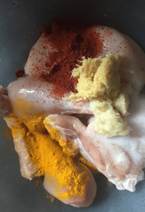 Adding salt, red chilli powder tumeric and ginger garlic paste to chicken legs - Tandoori Chicken Recipe